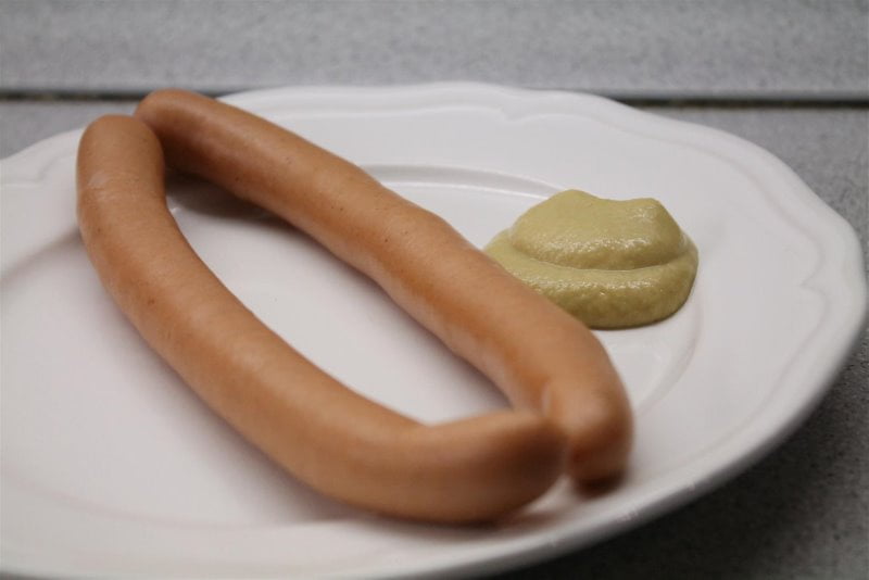 Boiled hot dogs with mustard on a plate