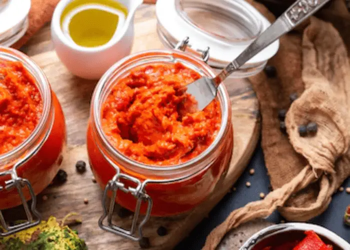 Ajvar on the table with vegetables and spices around
